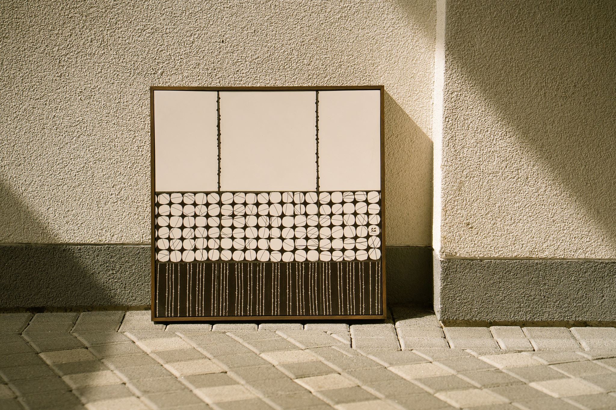 Heġe, contemporary abstract polymer clay artwork featuring three minimalist off-white panels above bands of black-and-off white circular cane patterns and fine vertical stripes, framed in a dark English walnut stained wooden tray frame.
