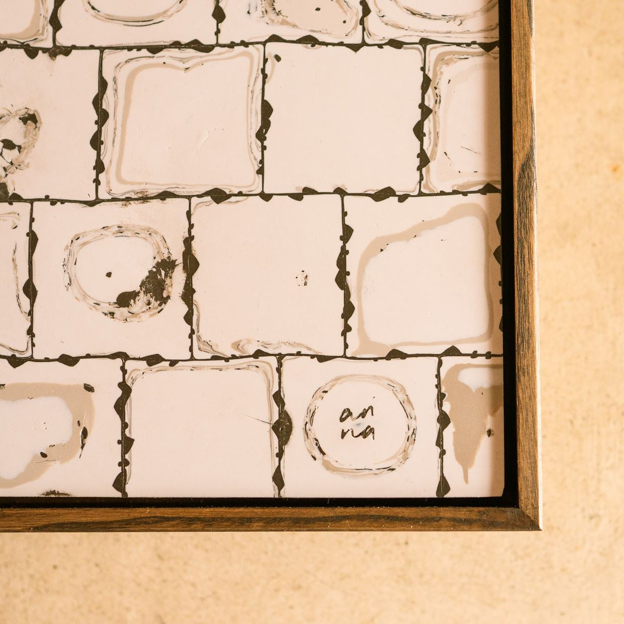 Close-up of contemporary abstract polymer clay wall artwork by Studio Anna, featuring hand-cut square cane slices arranged in a geometric grid with layered neutral patterns in off-white and dark brown/black.