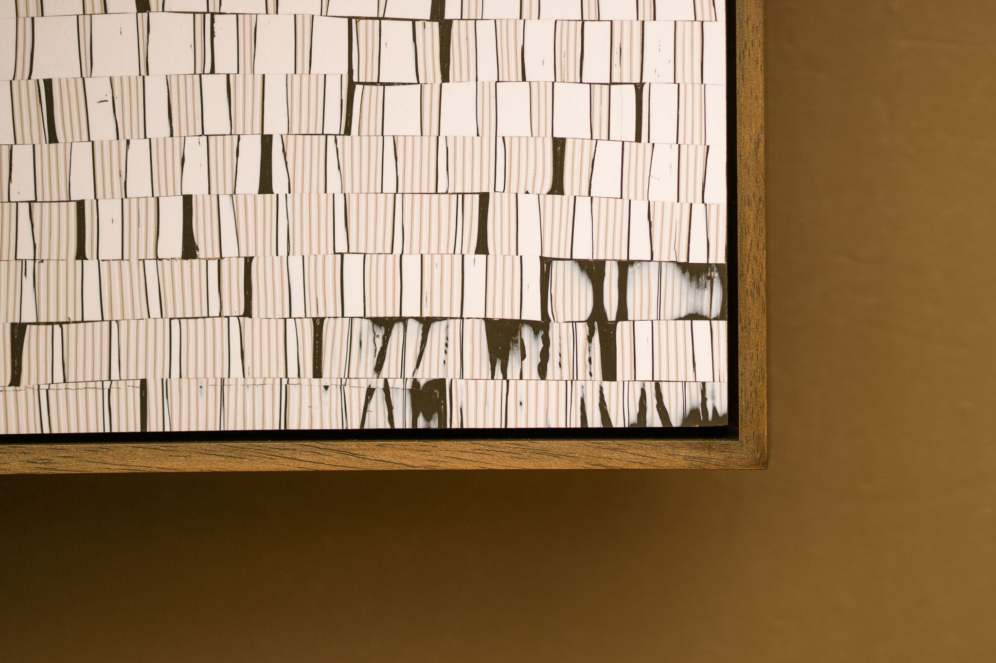 Close-up of Wer showing a detail of layered dark brown and cream striped cane work, framed in a stained wooden tray frame.