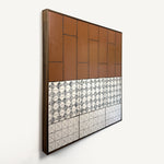 Drȳge, a contemporary abstract polymer clay artwork measuring 78 × 78 cm, by artist Anna Mills. Photographed at an angle. A bold composition contrasts a large field of warm terracotta with two patterned ivory bands below, featuring intricate black geometric motifs and fine linear grids. Delicate black linework and subtle handcrafted surface variations emphasise the balance between architectural order and organic imperfection. Presented in a solid wood tray frame finished in dark English walnut.