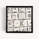 Ēa (Study III), a contemporary abstract polymer clay artwork composed of a grid of off-white toned square tiles featuring organic circular impressions, fragmented textures and subtle grey marbling. Dark brown grout-like lines and irregular edges emphasise the handmade surface, creating a quiet dialogue between order and erosion. Presented in a solid wood veneer tray frame finished in dark English walnut, measuring 17 × 17 cm.