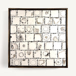Ēa (Study II), a contemporary abstract polymer clay artwork, by Anna Mills, composed of a grid of individually hand-cut cane tiles, each revealing unique concentric patterns created from layered clay. Soft ivory, warm grey and dark brown/black tones evoke geological formations and topographic contours, while the irregular tile edges and subtle surface variations celebrate the handmade process. Presented in a solid wood tray frame finished in dark English walnut.