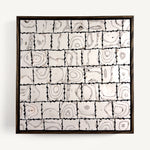 Ēa (Study I), a contemporary abstract polymer clay artwork, by Anna Mills, composed of a grid of individually hand-cut cane tiles, each revealing unique concentric patterns created from layered clay. Soft ivory, warm grey and dark brown/black tones evoke geological formations and topographic contours, while the irregular tile edges and subtle surface variations celebrate the handmade process. Presented in a solid wood tray frame finished in dark English walnut.