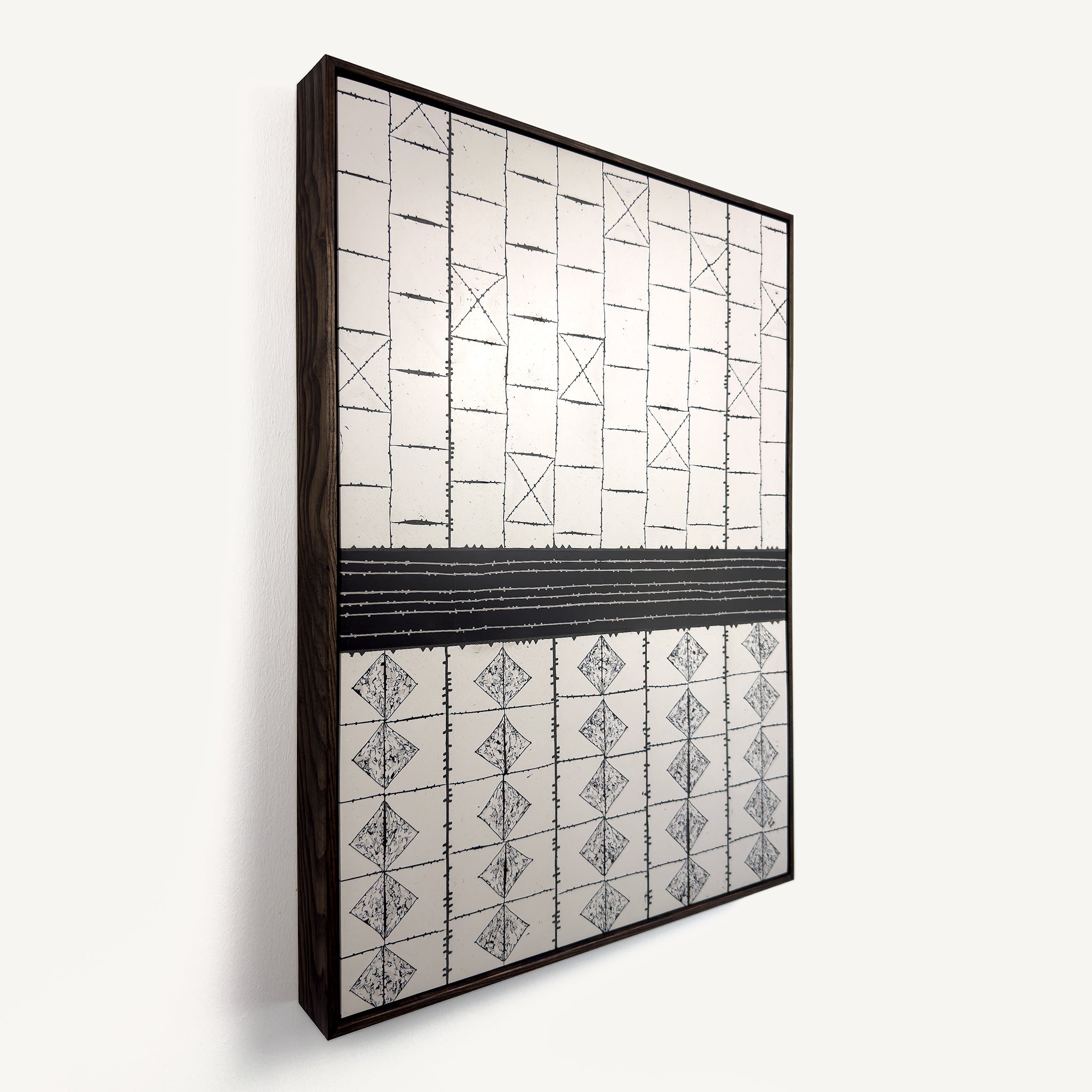 Ende, a contemporary abstract polymer clay artwork composed of geometric off-white and black forms arranged in a structured grid. The upper section features rectangular blocks interrupted by occasional crossed squares, while the lower section is defined by repeating diamond motifs. A bold horizontal dark brown black band divides the composition, creating a strong architectural balance between the two halves. Presented in a solid wood tray frame finished in dark English walnut, measuring 47.5 × 63 cm.