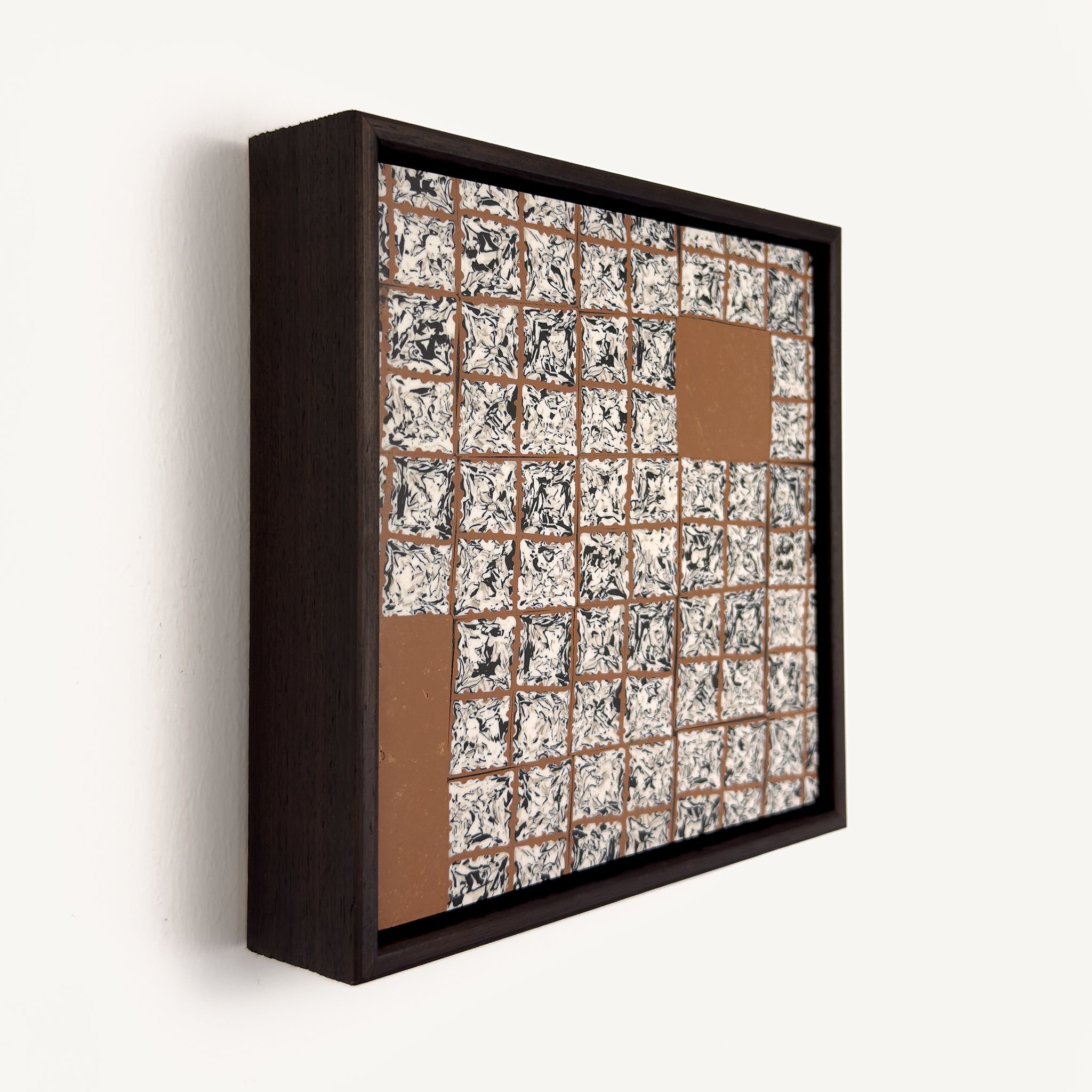 Greót II, at an angle, a contemporary abstract polymer clay artwork featuring a grid of individually sliced black, white and beige patterned squares arranged around open terracotta-coloured negative spaces. The composition is presented in a solid wood veneer tray frame finished in dark English walnut, measuring 17 × 17 cm.