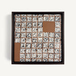 Greót II, by artist Anna Mills, a contemporary abstract polymer clay artwork featuring a grid of individually sliced black, white and beige patterned squares arranged around open terracotta-coloured negative spaces. The composition is presented in a solid wood veneer tray frame finished in dark English walnut, measuring 17 × 17 cm.