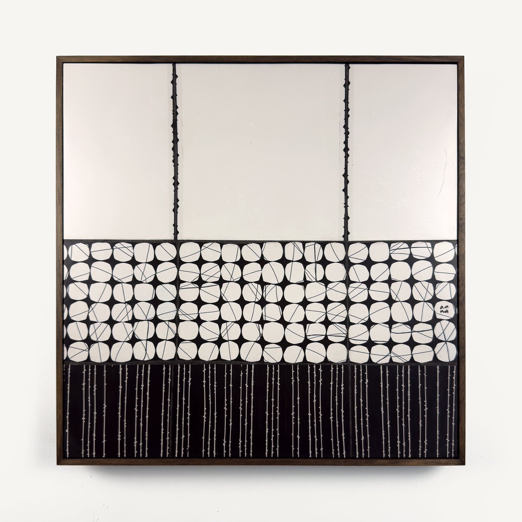 Heġe, a contemporary abstract polymer clay artwork measuring 52 × 52 cm, by artist Anna Mills. A minimalist composition combines a spacious off-white upper field with a central band of hand-cut organic geometric forms outlined by fine black lines, anchored by a bold black section of delicate vertical linework below. Subtle handcrafted textures and irregularities create a quiet balance between structure and organic movement. Presented in a solid wood tray frame finished in dark English walnut.