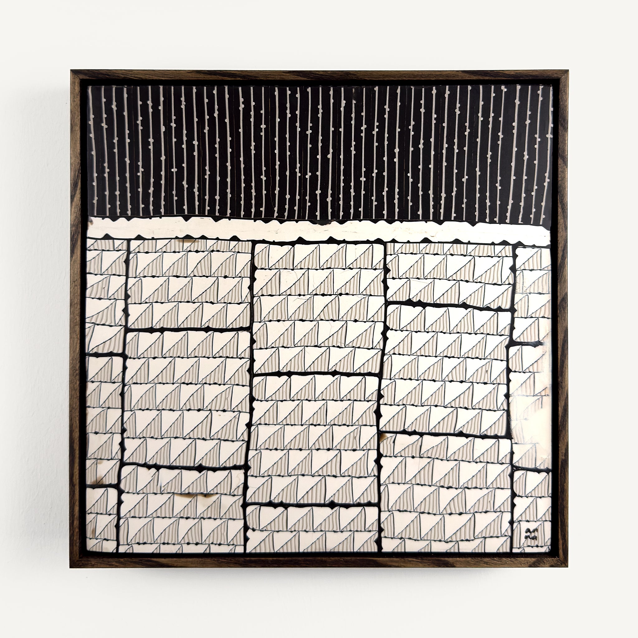 Steppe, a contemporary abstract polymer clay artwork measuring 32 × 32 cm, by artist Anna Mills. A bold black upper section of fine vertical lines contrasts with a structured arrangement of hand-cut ivory geometric tiles below, each marked with delicate linear details. Irregular edges, subtle surface variations and visible handcrafted textures create a quiet balance between order and organic imperfection. Presented in a solid wood tray frame finished in dark English walnut.