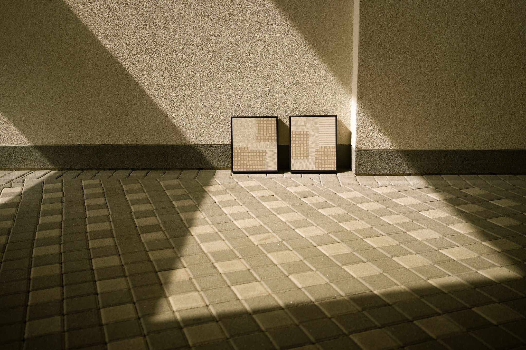 Urbis I and Urbis II, paired contemporary abstract polymer clay artworks featuring layered geometric patterns in soft greige and off-white, displayed against a minimalist architectural wall in natural light.