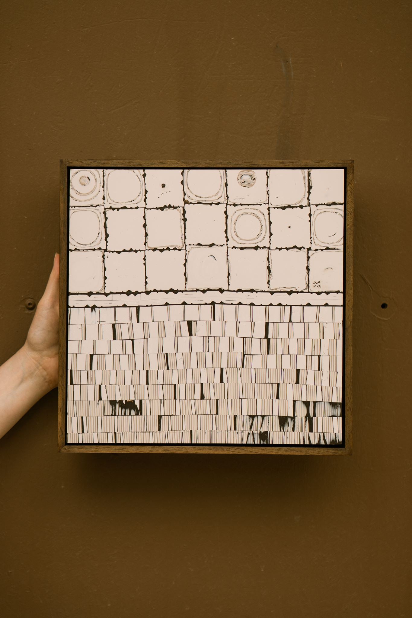 Contemporary abstract polymer clay artwork, titled: Wer, combining hand-cut square cane slices with finely layered dark brown and cream striped cane work, framed in a stained wooden tray frame.